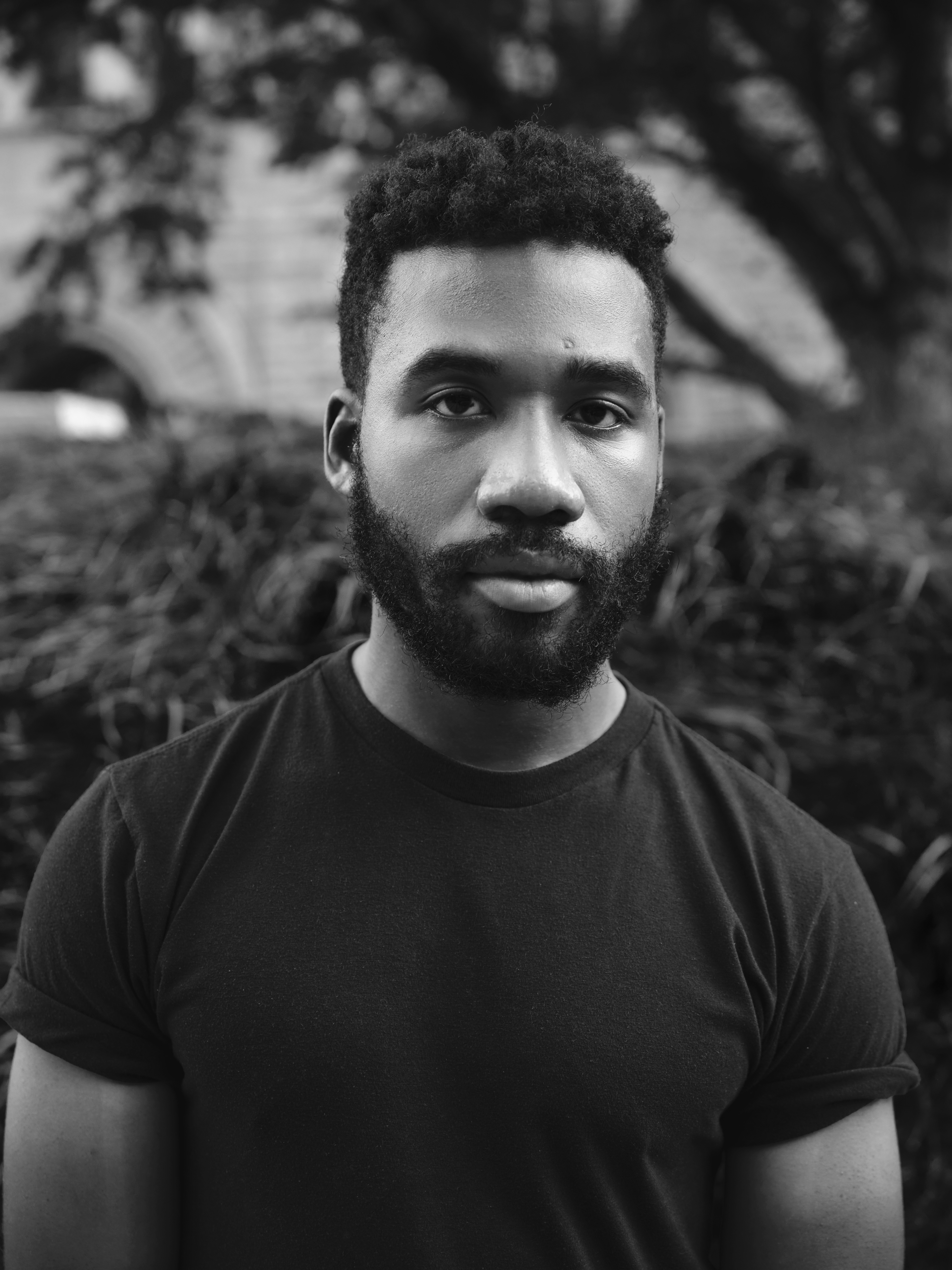 Portrait of Joshua Rashaad McFadden from torso up wearing a t-shirt looking into the camera