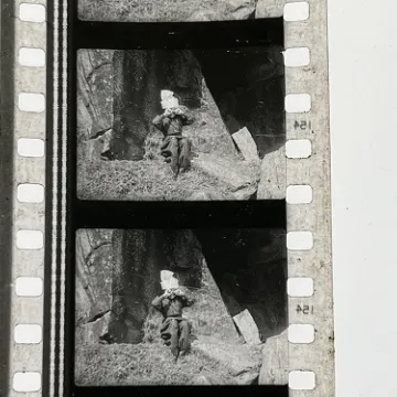 35mm film fragment depicting boy crying on rock.