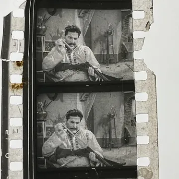 35mm film fragment depicting a man cleaning a shotgun.