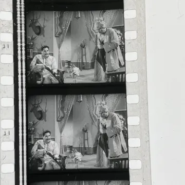 35mm film fragment depicting a man cleaning a shotgun.
