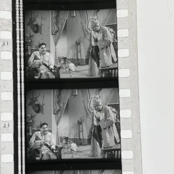 35mm film fragment depicting a man cleaning a shotgun.