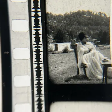 35mm film fragment depicting a woman in a chair.