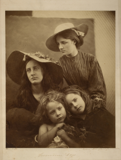 Victorian women wearing sun hats holding onto two younger girls