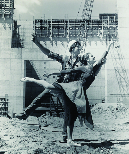 Ballet dancer posing with construction worker on work site, circa 1975, by Basil C. Levine