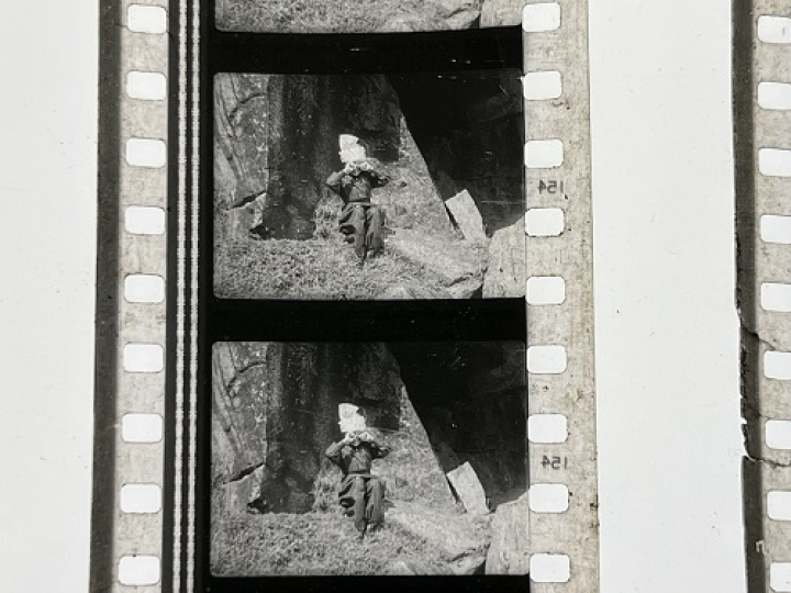 35mm film fragment depicting boy crying on rock.