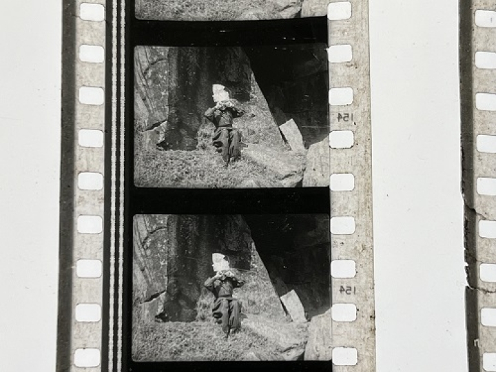 35mm film fragment depicting boy crying on rock.