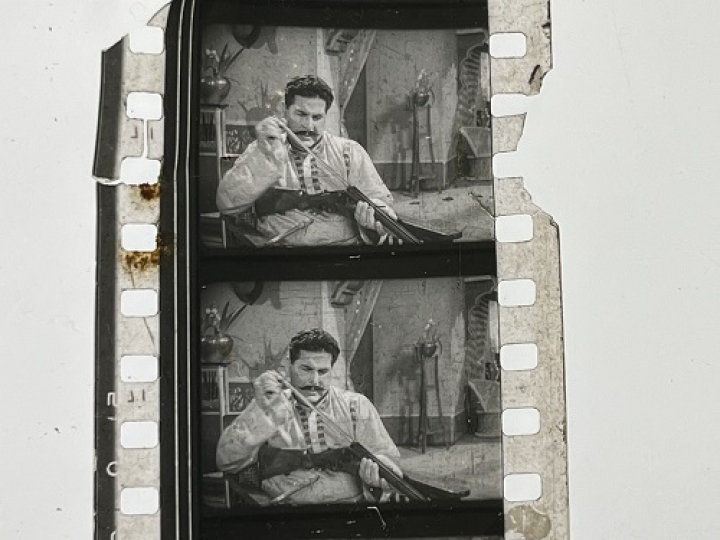 35mm film fragment depicting a man cleaning a shotgun.