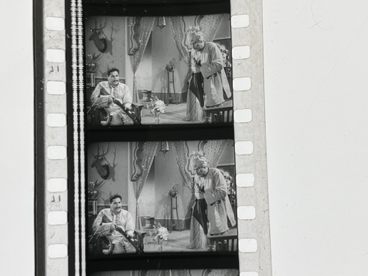 35mm film fragment depicting a man cleaning a shotgun.
