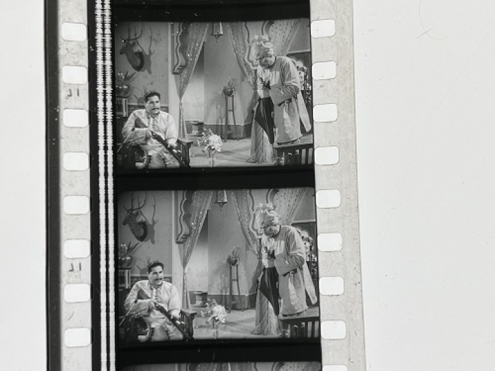 35mm film fragment depicting a man cleaning a shotgun.
