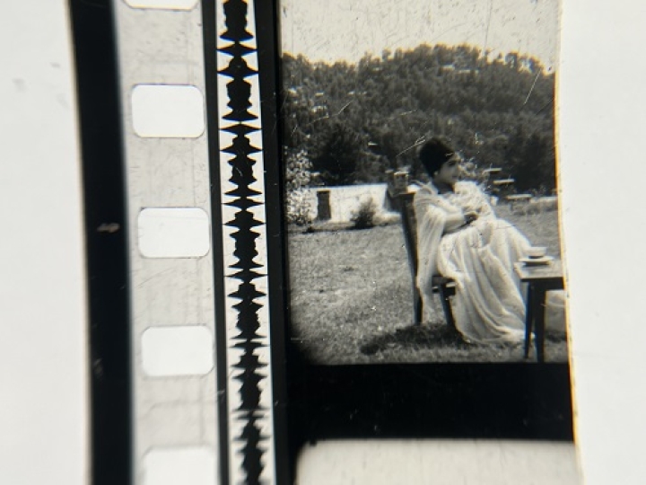 35mm film fragment depicting a woman in a chair.
