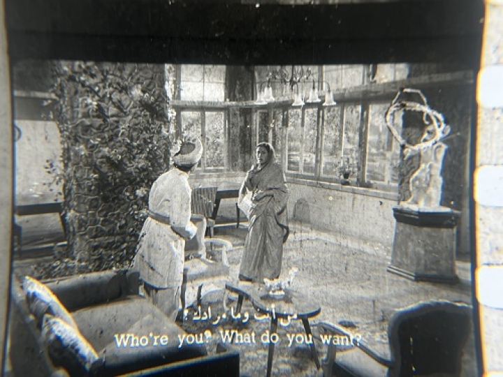 35mm film fragment depicting a woman talking with a man.