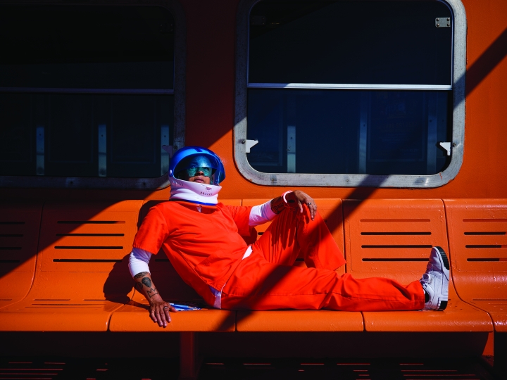 Lola Flash image of astronaut in orange suite sitting on an orange bench
