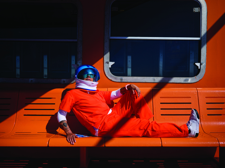 Lola Flash image of astronaut in orange suite sitting on an orange bench