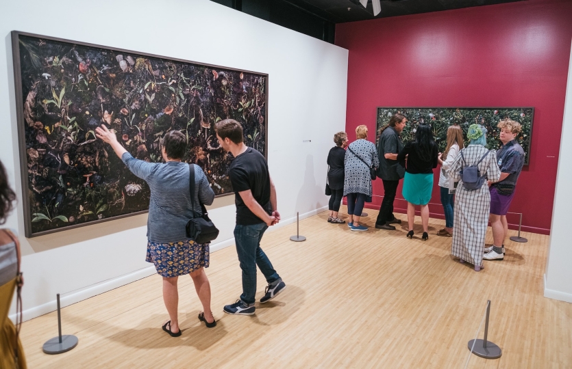 Individuals in the Woven exhibition looking at the photographs