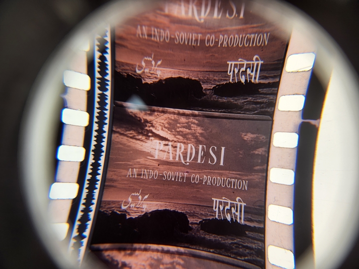 Magnified motion picture film strip depicting an ocean scene overlaid with the words Pardesi, An Indo-Soviet Production