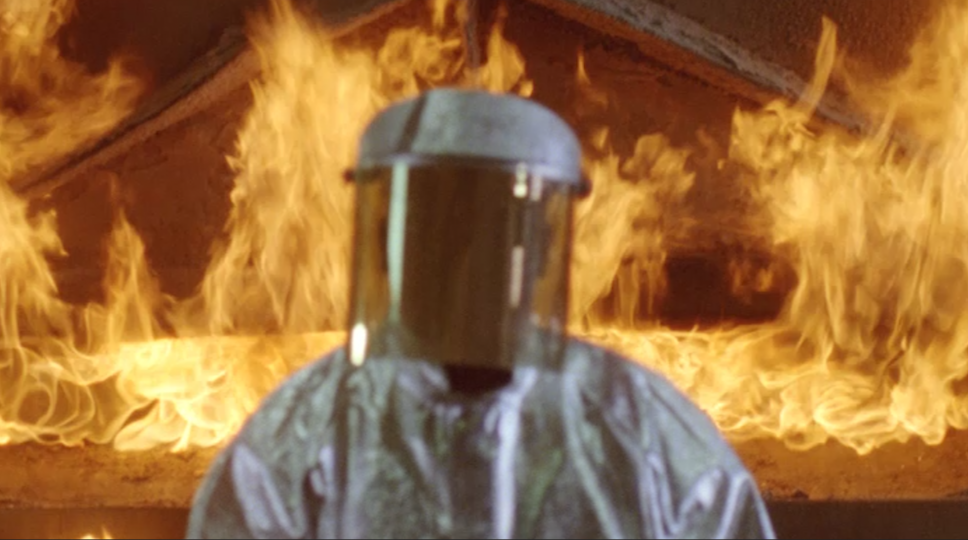Person in a hazard suite in front of fire