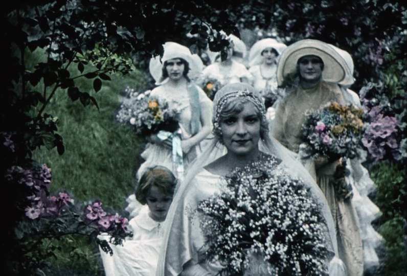 A hand painted film still that was black and white. A bride holds flowers with her procession behind her also holding flowers.