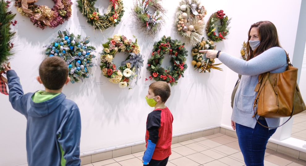 Two boys and a woman looking at wreaths