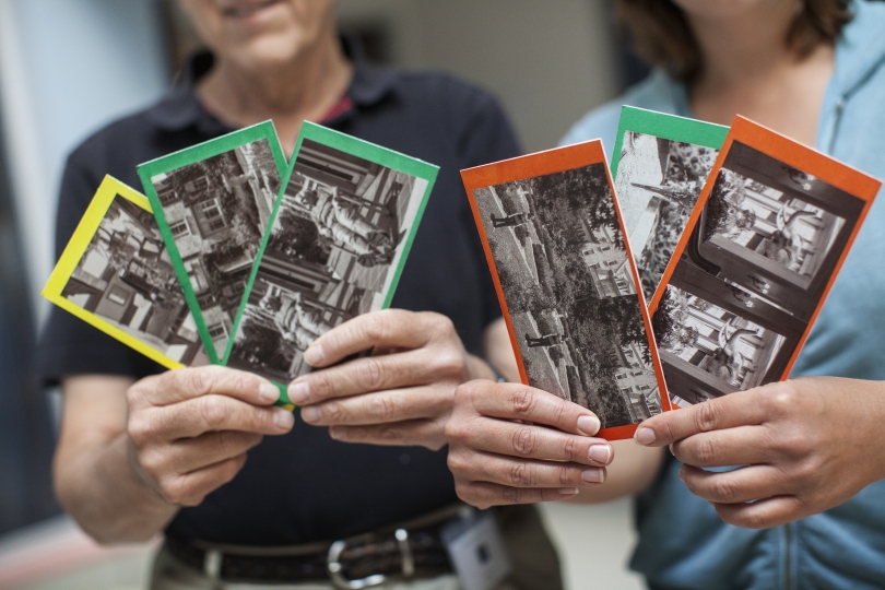 Two people holding up stereocard examples