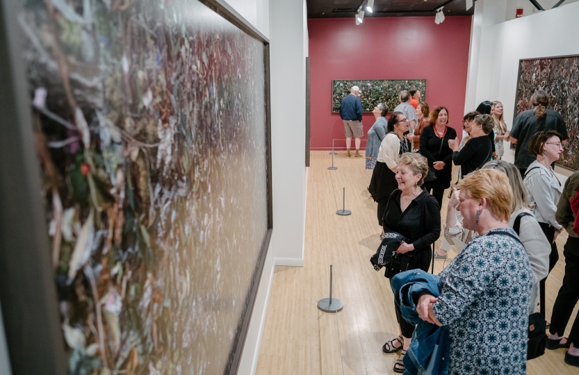 Individuals in the Woven exhibition looking at the photographs
