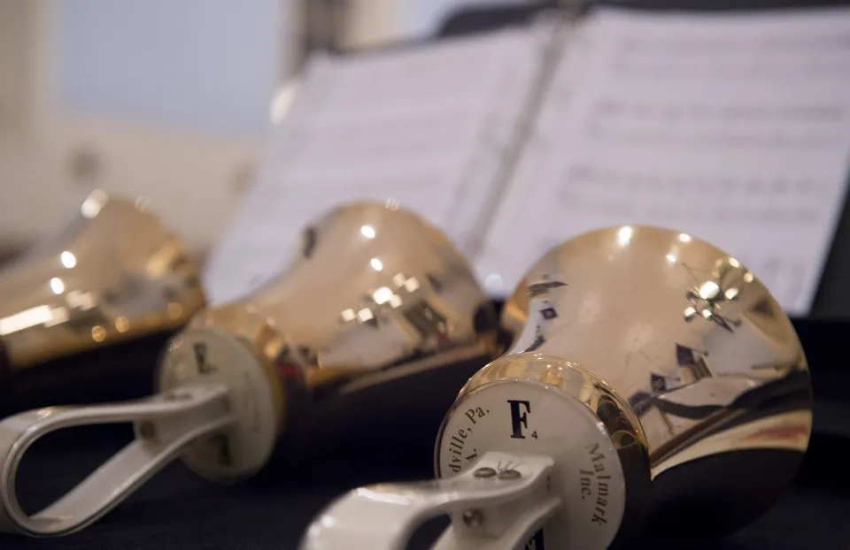 Handbells with sheet music in backgrouond