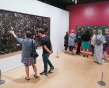 Individuals in the Woven exhibition looking at the photographs