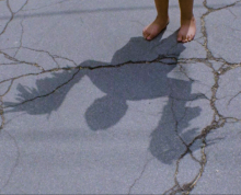A shadow over concrete that looks human/bird like