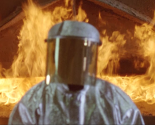 Person in a hazard suite in front of fire