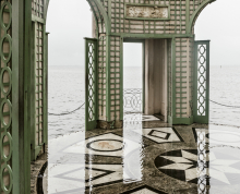 Ornate interior with body of water visible through three doorways and water over patterned marble floor