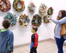 Two boys and a woman looking at wreaths