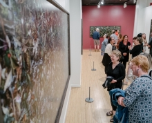 Individuals in the Woven exhibition looking at the photographs