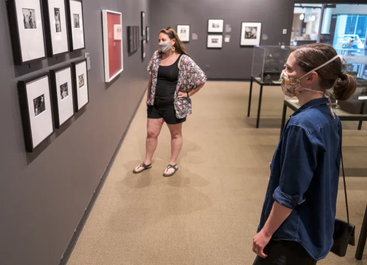 Two guests wearing masks looking at photographs in a gallery