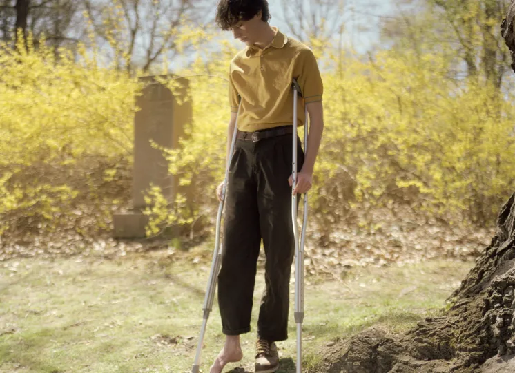 Portrait of a young person missing a shoe and is on crutches