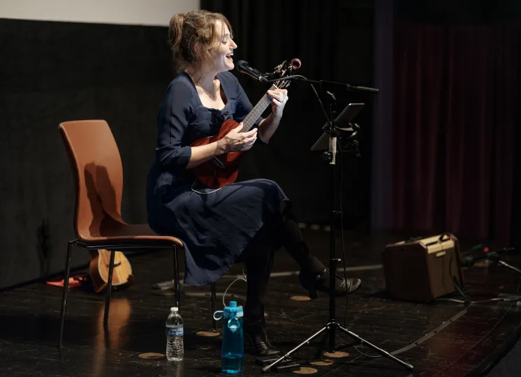 Maggie Paxson singing and playing ukulele in a performance at the George Eastman Museum