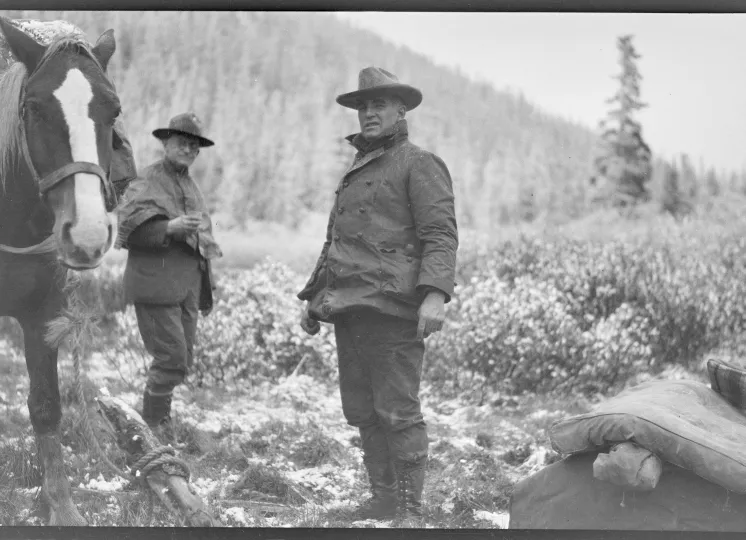 George Eastman and another man dressed in warm clothes outside in Alaska, George Eastman is leading a horse