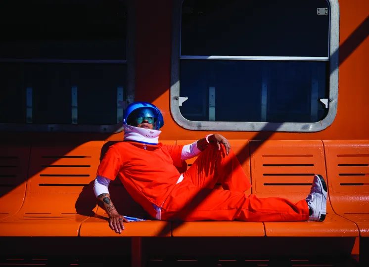 Lola Flash image of astronaut in orange suite sitting on an orange bench