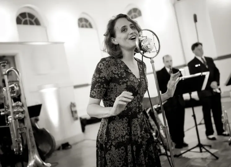 Photo of a young woman singing in a vintage microphone 