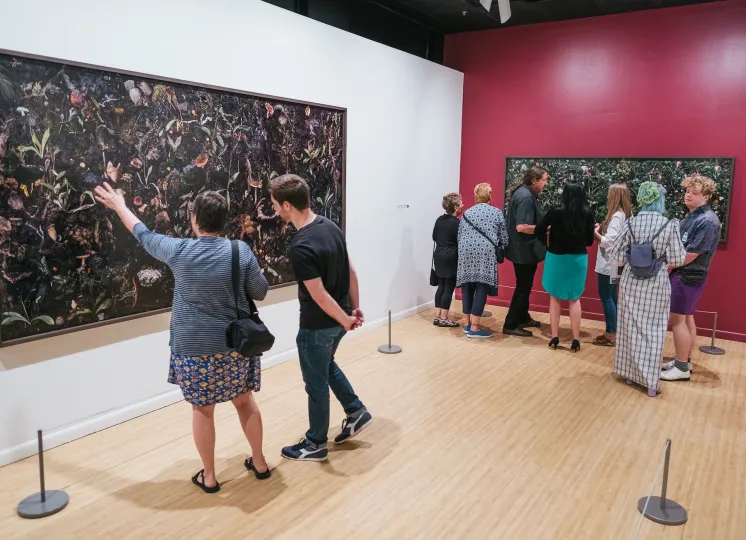 Individuals in the Woven exhibition looking at the photographs