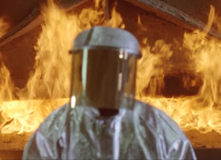 Person in a hazard suite in front of fire