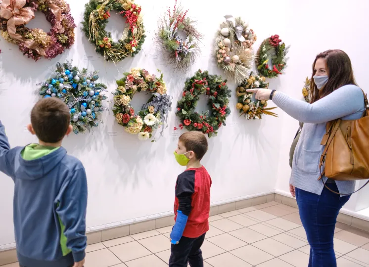 Two boys and a woman looking at wreaths