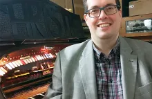 Headshot of Andreas Benz seated smiling at the camera next to an organ keyboard