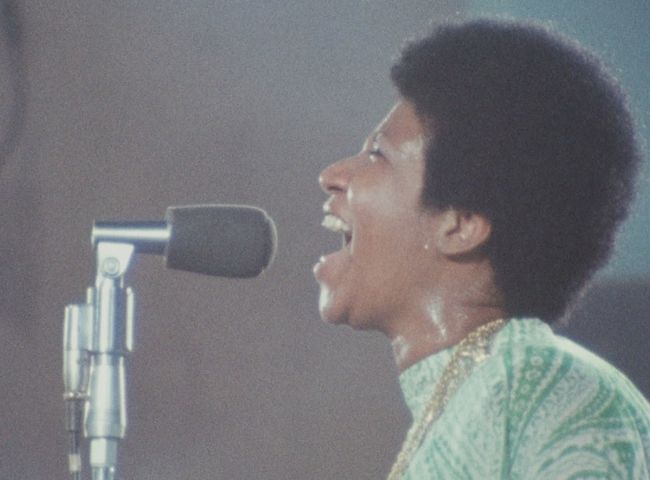 Still from the film Amazing Grace showing Aretha Franklin singing into a microphone