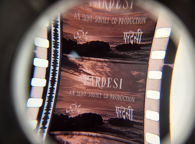 Magnified motion picture film strip depicting an ocean scene overlaid with the words Pardesi, An Indo-Soviet Production