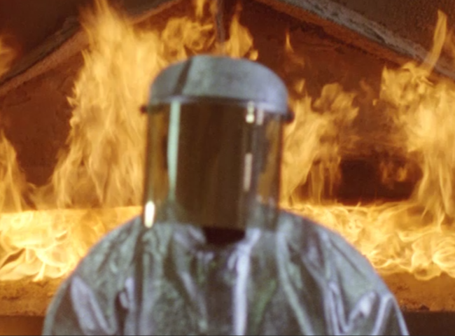 Person in a hazard suite in front of fire