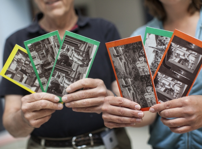 Two people holding up stereocard examples