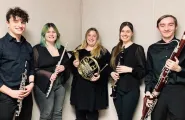 Five adult musicians stand side by side holding musical instruments