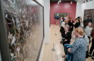 Individuals in the Woven exhibition looking at the photographs